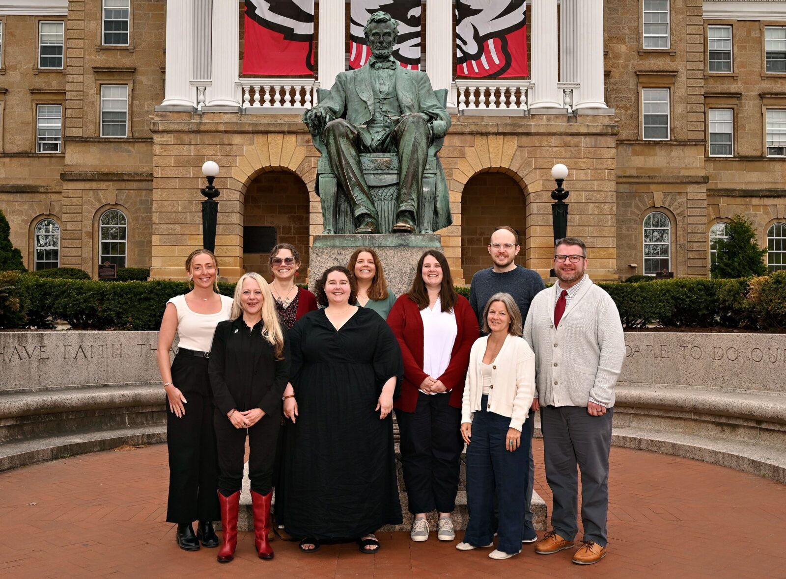 9 members of the OSAS staff standing in front of a Abraham Lincoln statue and Bascom Hall